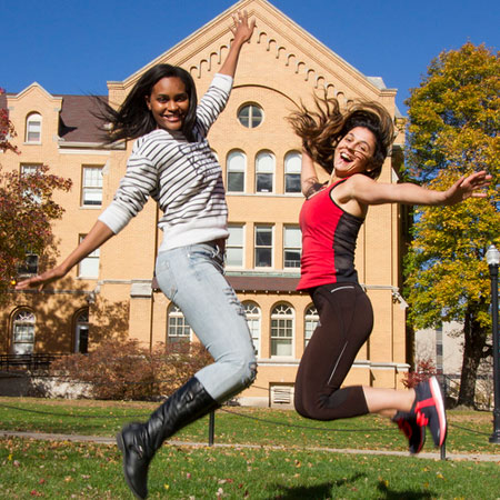 NIU students jumping in front of Williston Hall.