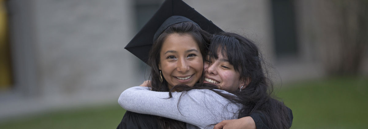Hispanic Female graduate student hugging family member