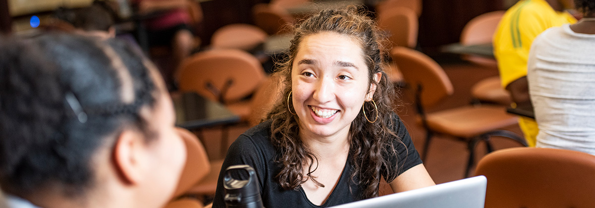 student smiling while talking to another student