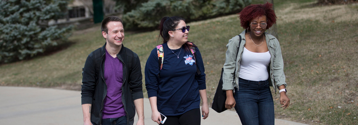 a trio of students chat with one another as they walk