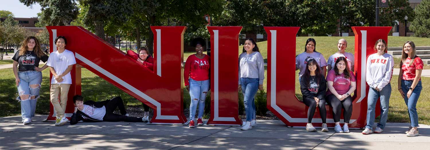Group of NIU students posing in front of the NIU letters sculpture.