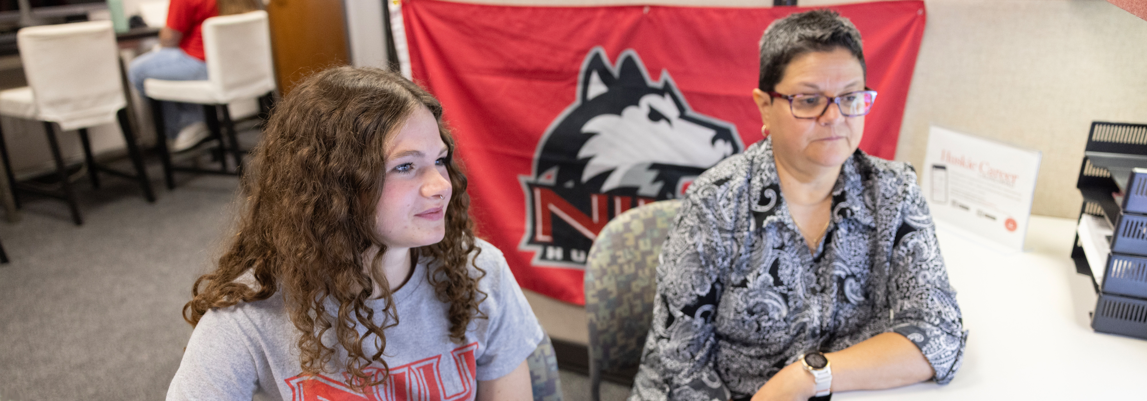 Two female students flipping through a book together