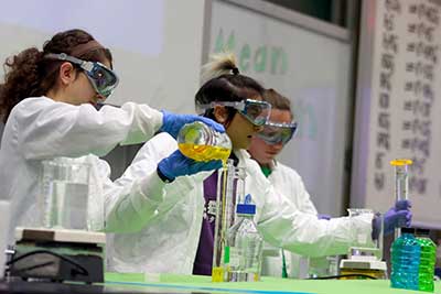 Female student in lab poring liquid from one beaker into another