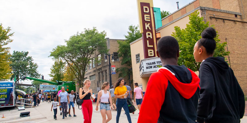 Students with DeKalb sign on a building in downtown DeKalb