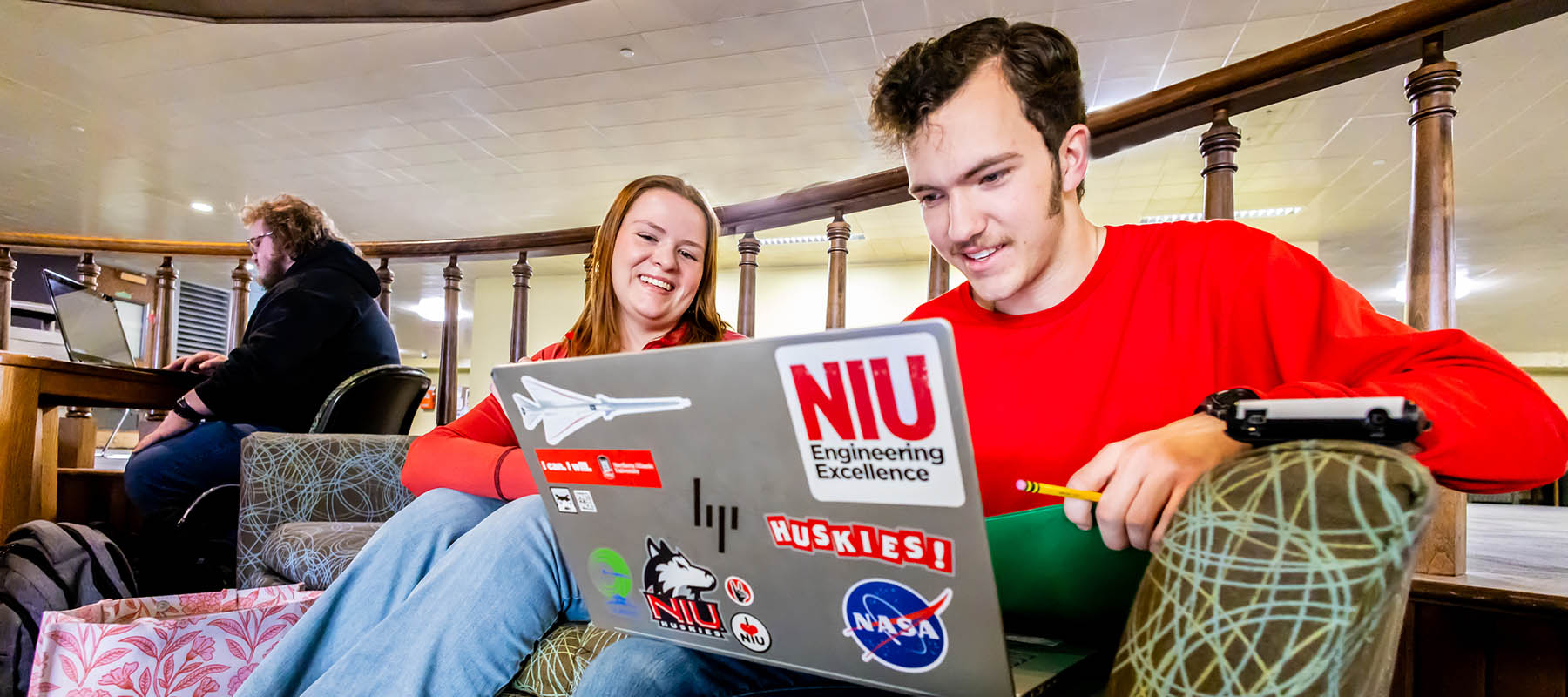 student working on laptop with another student looking over shoulder at laptop