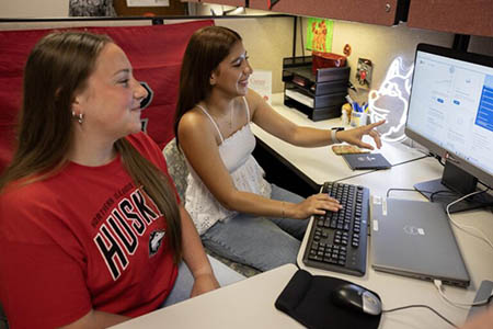 two students sitting side-by-side working on a computer