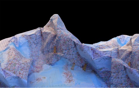 Photograph of geographic map folded into mountainous terrain