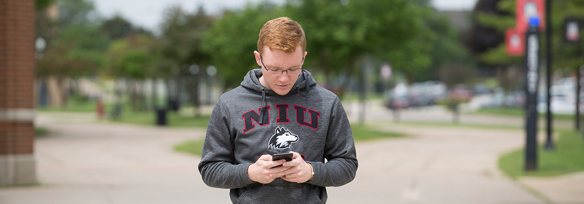 student walking outside while using mobile app