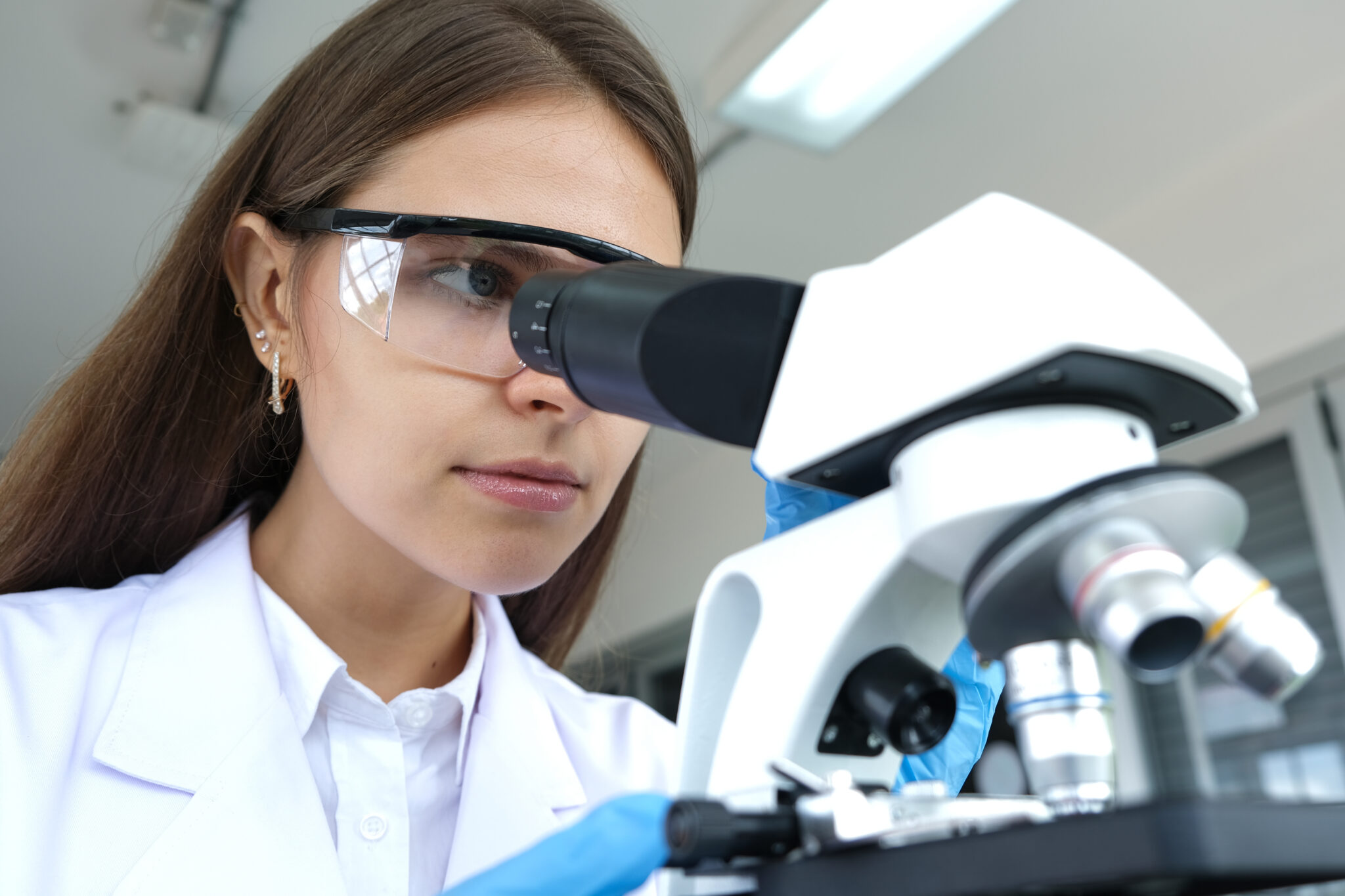 female student in science lab looking through microscope