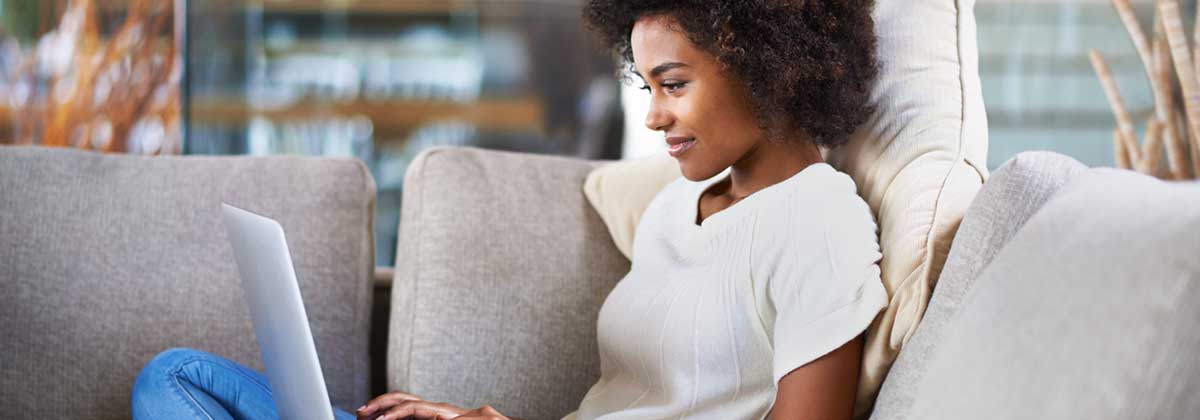 student sitting on a couch working on a laptop
