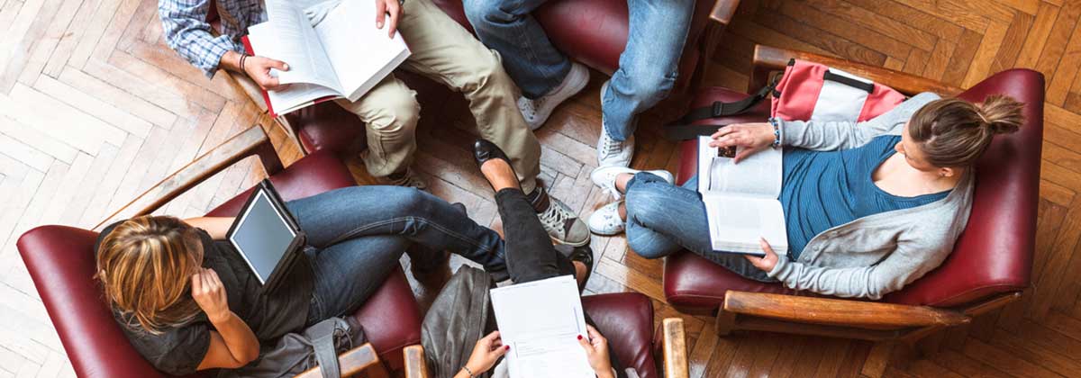 four students sitting in chairs view course materials