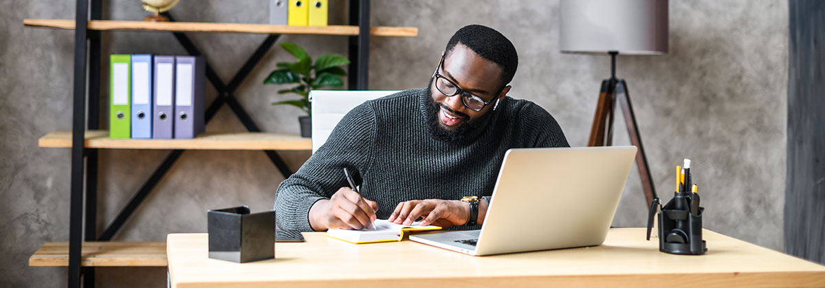 Black man professor using a laptop at a desk in a home office