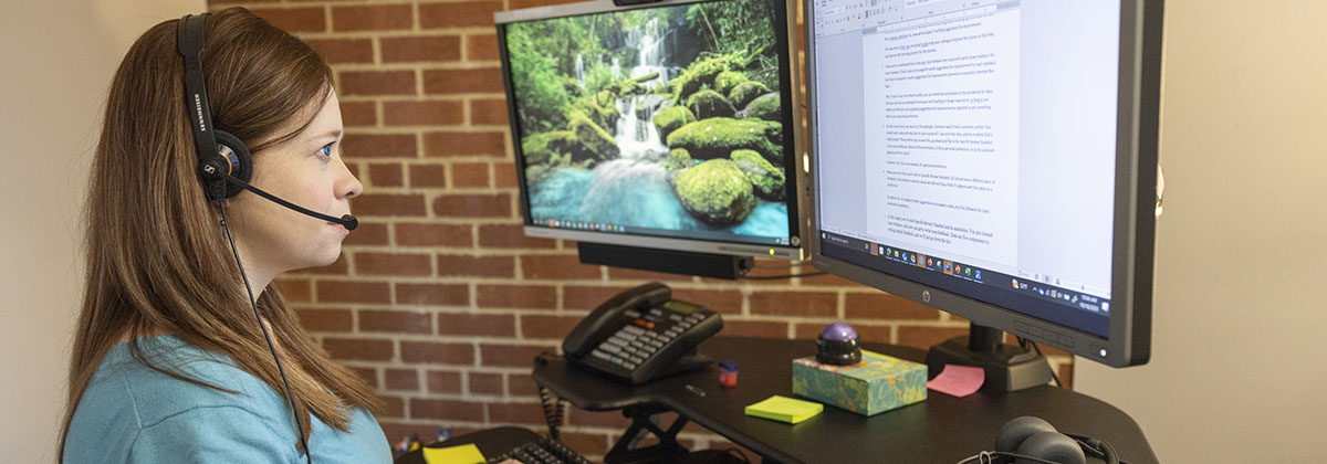 woman wearing headphones looking at computer monitor