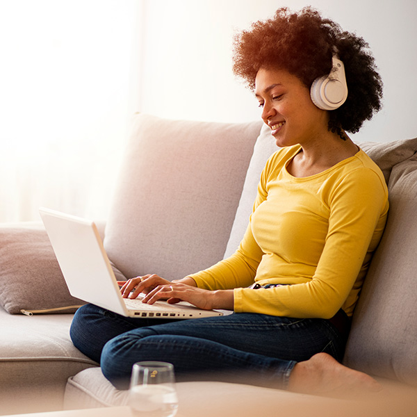 woman sitting on sofa with laptop and headphones
