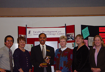 six people proudly holding a brass statue