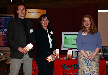 three people stand in front of a sign that reads "elearning services"
