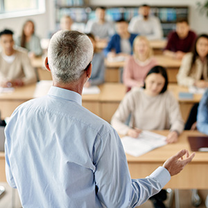 rear view of a male professor teaching to a classroom full of students