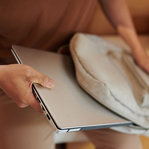 close-up of a hand putting a laptop into a backpack