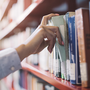 close-up of a hand taking a library book from the shelf