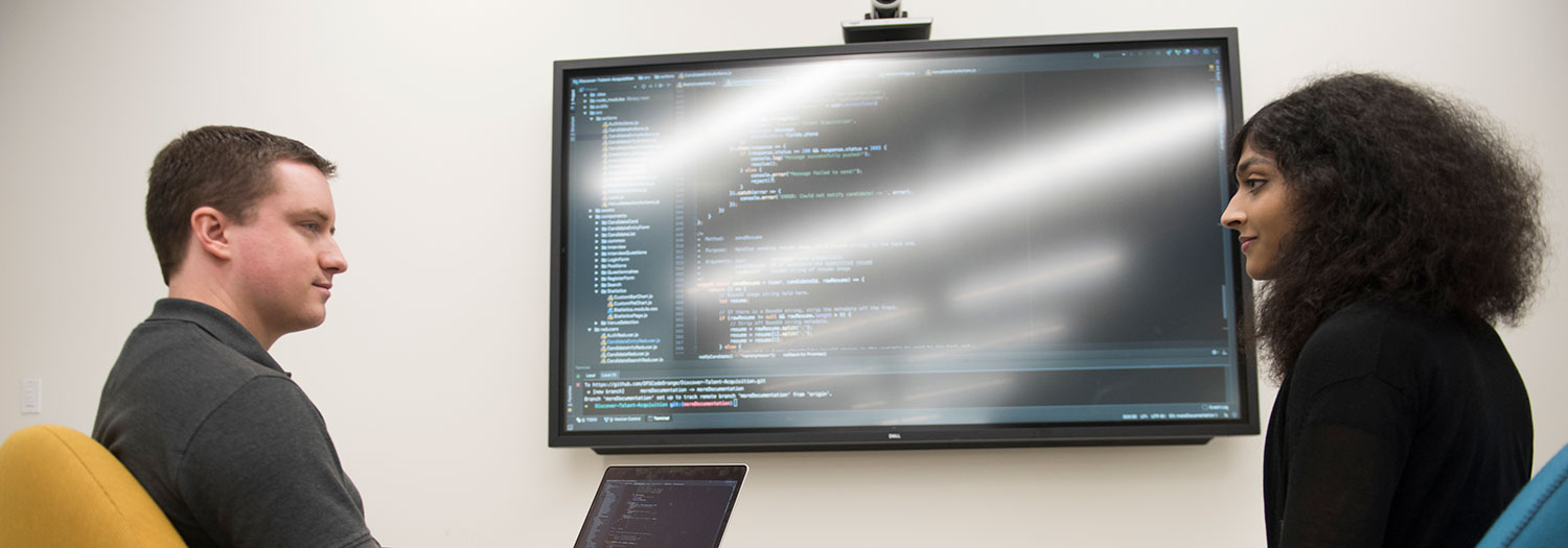 Two students discuss and review code for a project