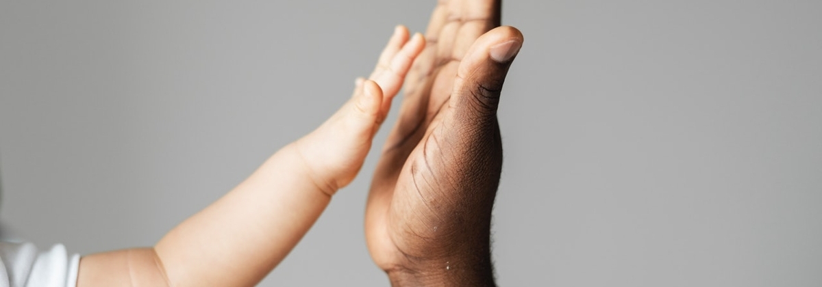 Close up of adult hand palm-to-palm with child hand