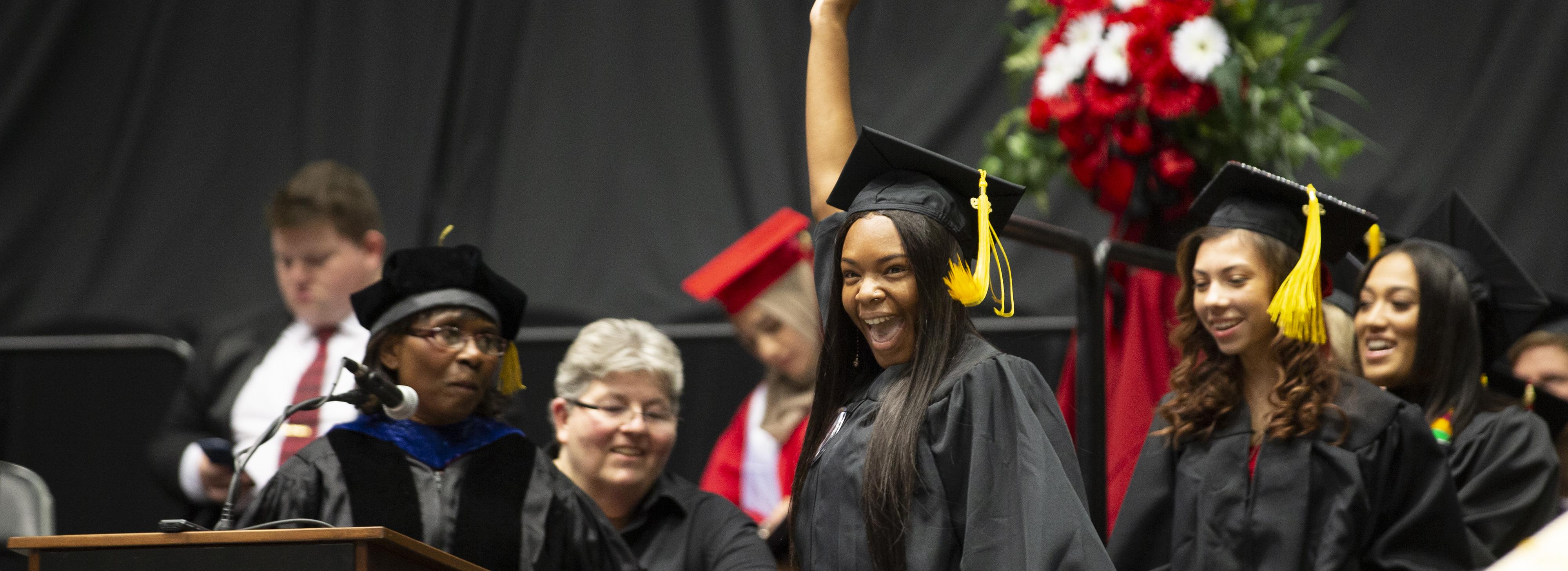 Student cheering as she walks across the Commencement stage