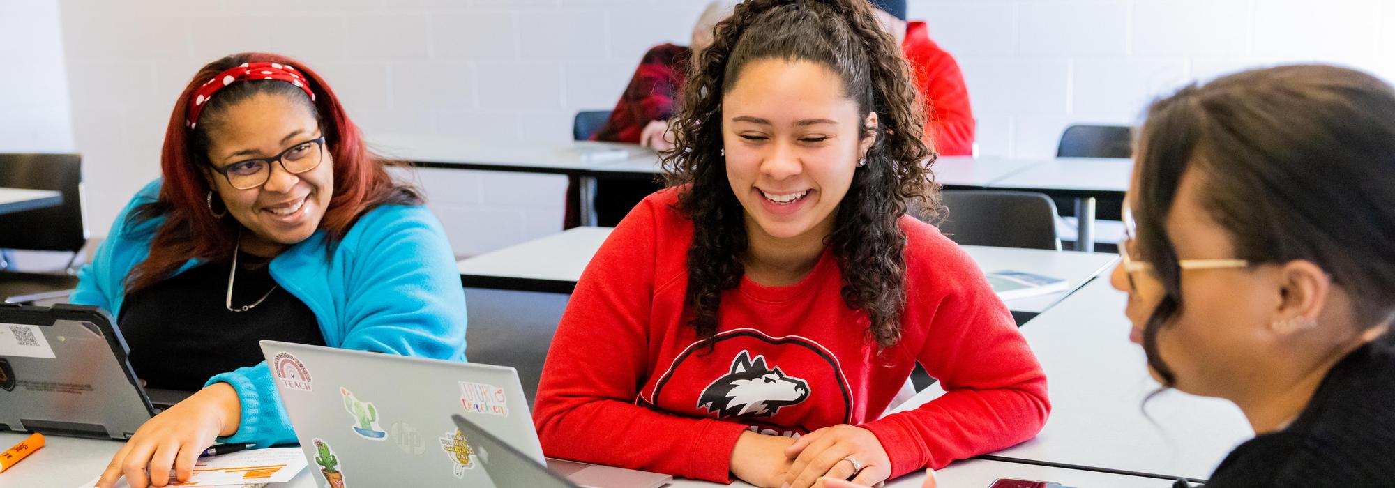 Student teacher assisting student reading textbook
