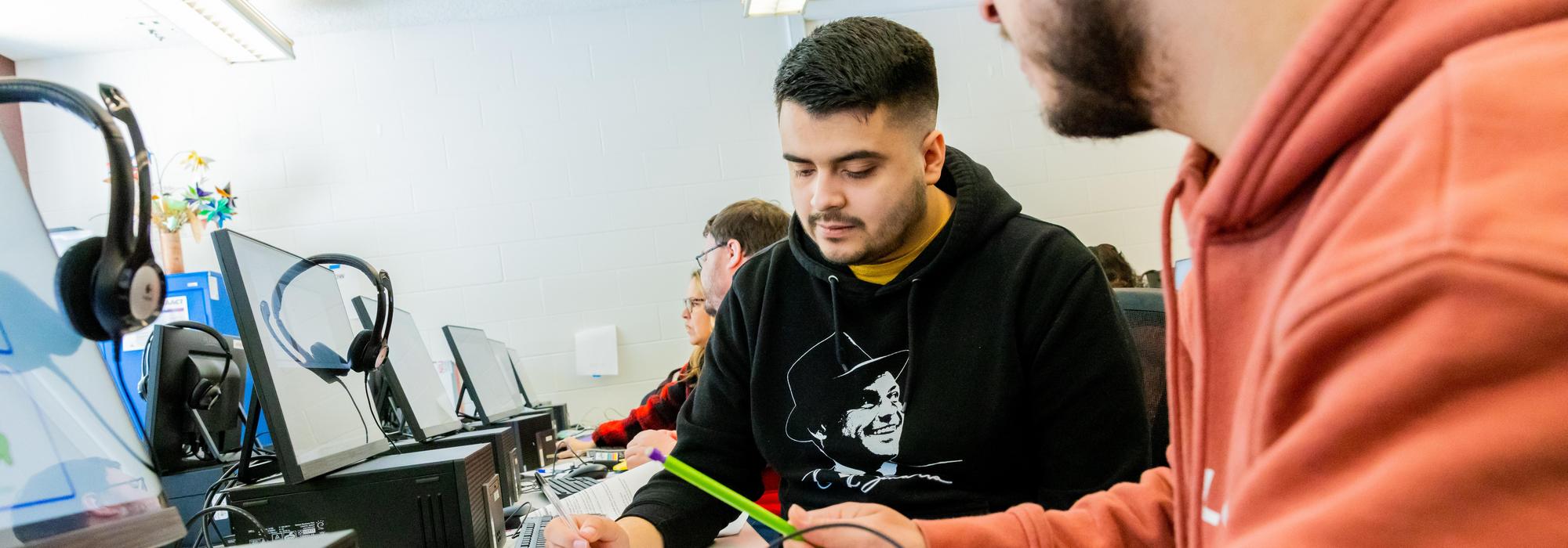 Student studying at table with laptop.