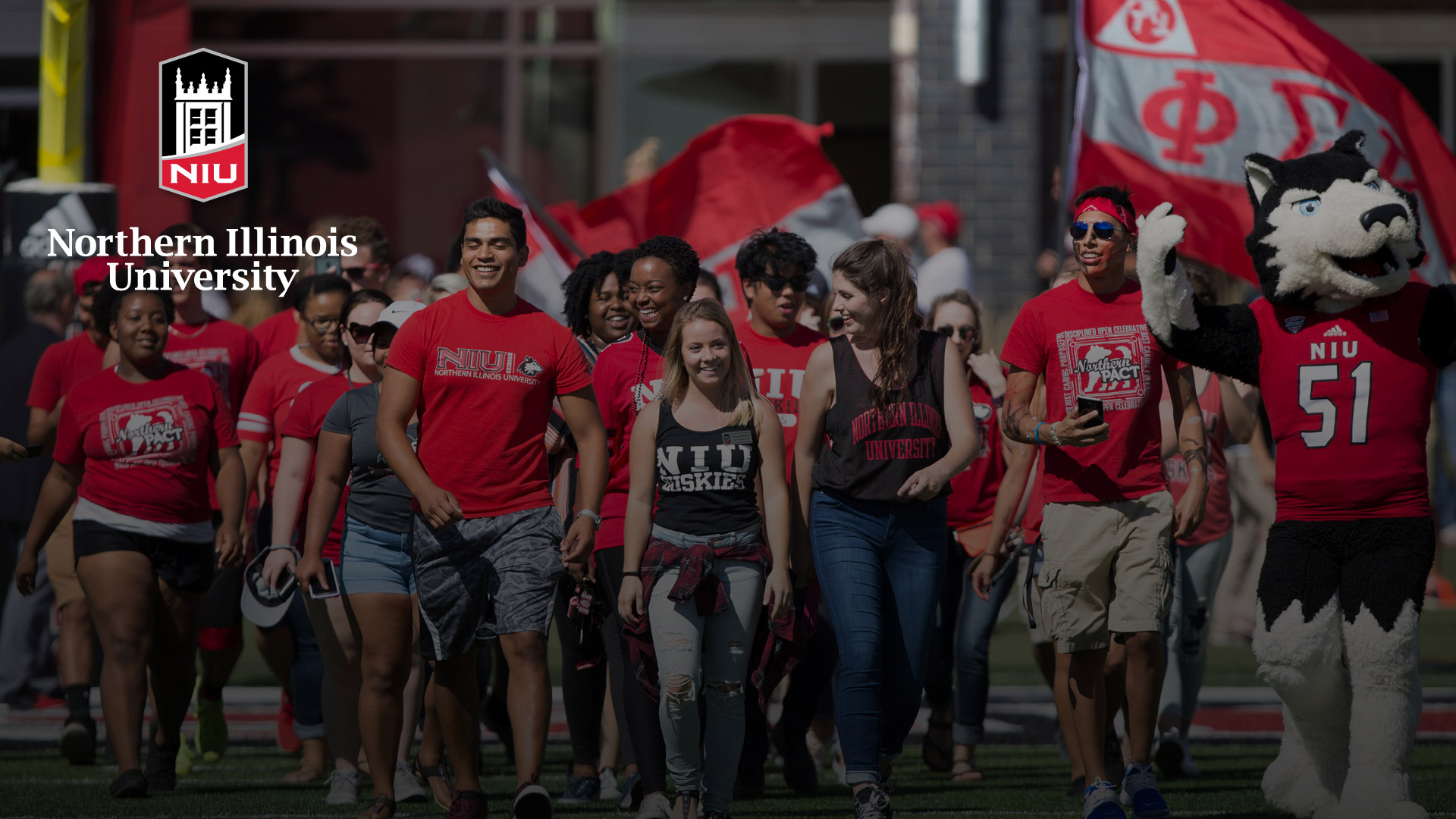 Zoom background - students in NIU gear with Victor E. Huskie
