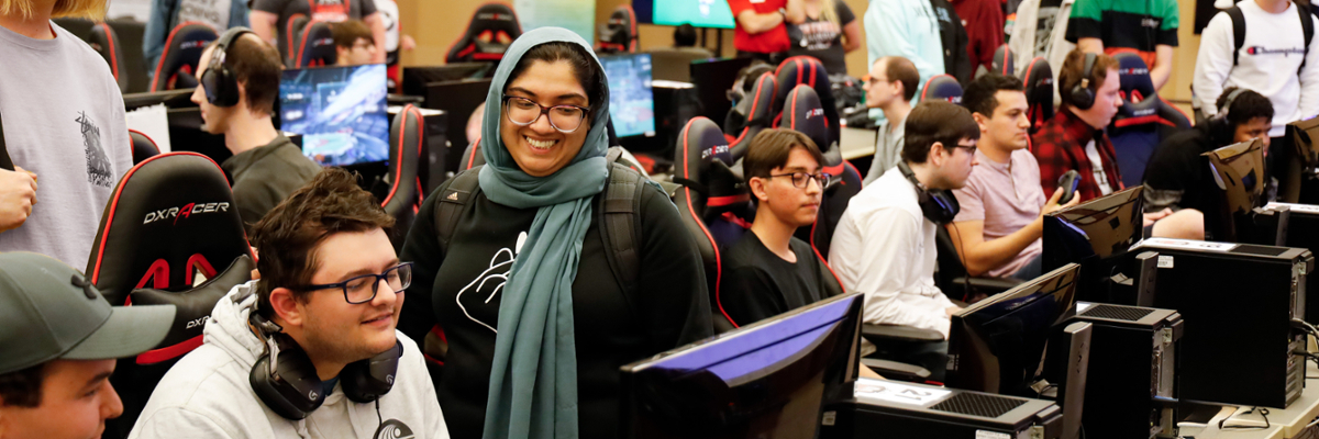 Smiling students playing video games together in the Esports Arena.