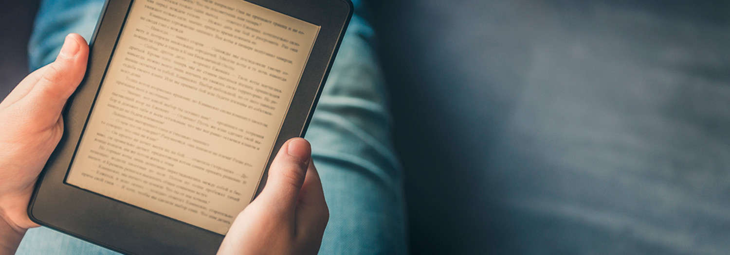 girl reading ebook while relaxing on a couch