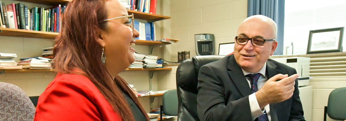 NIU professors Medhi Semati and Karla Padron talking together in an office.