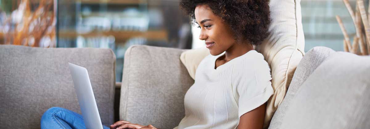 female student sitting on couch with laptop