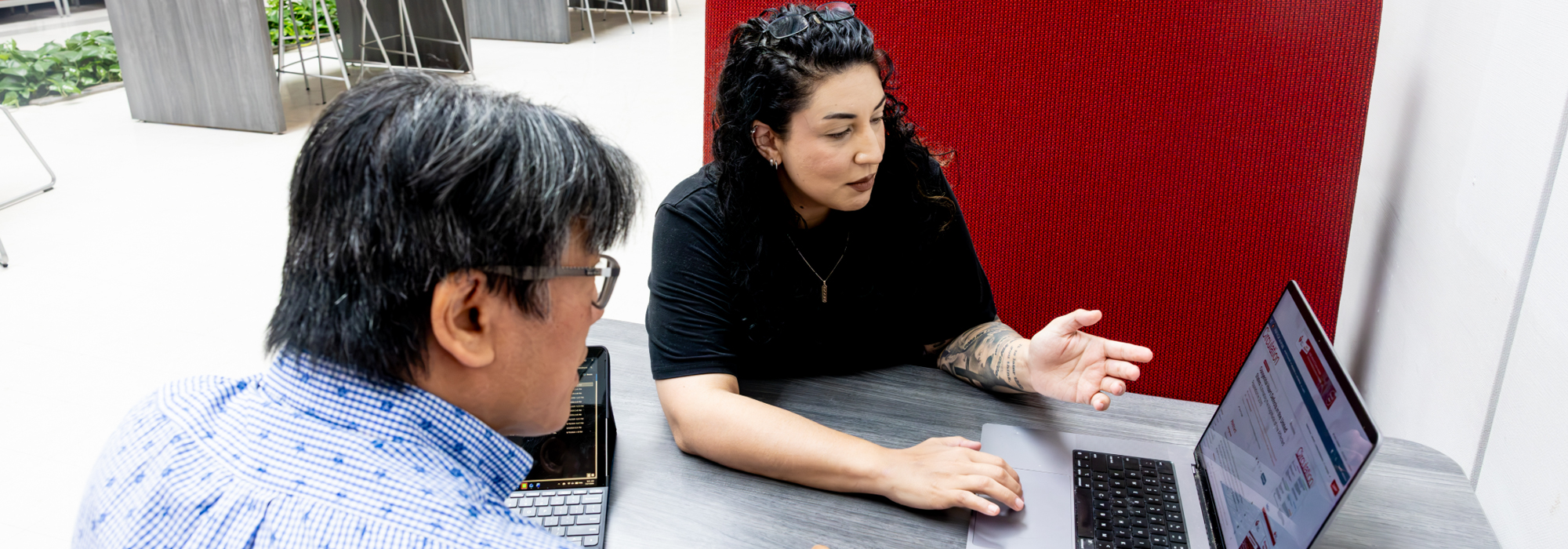 Woman and a student sitting at a table looking at a laptop