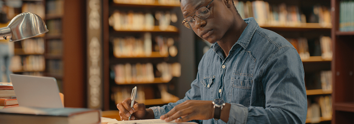 Student sitting at a desk in a library writing