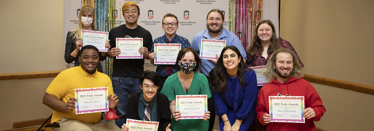 Group photo taken at the 2022 Pride Awards Ceremony. Members of Speakers Bureau are seen in the photo wearing colorful attire and smiling in front of a NIU backdrop