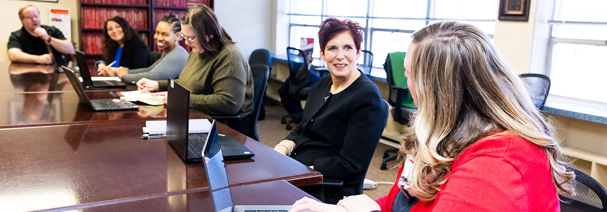 five faculty sitting at a conference table discussing