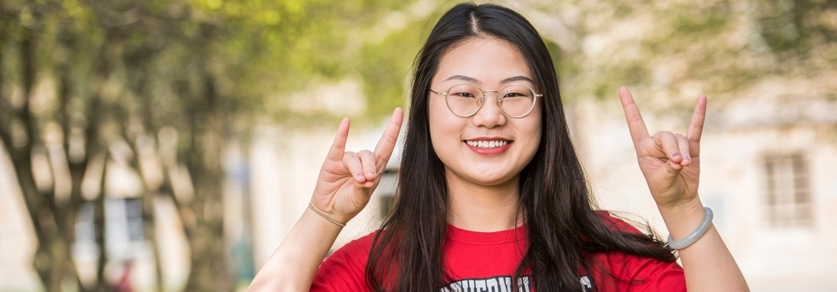 Siyu Tao, one of NIU's international students, making the huskie hand gesture.
