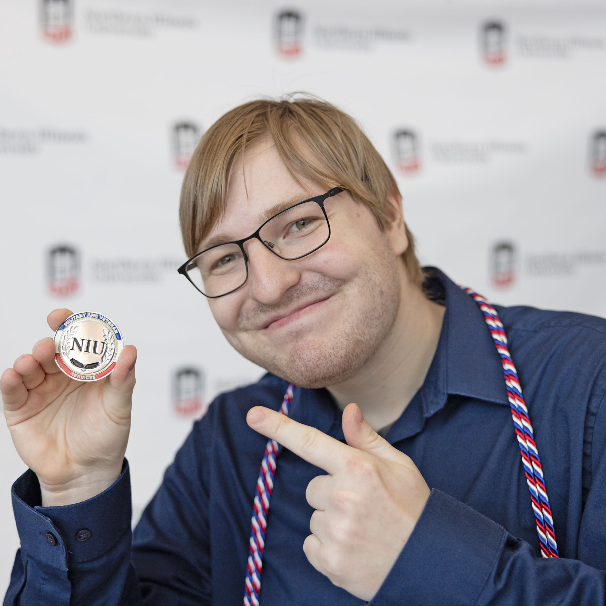 A military-connected graduate holds the NIU Military and Veteran Services coin
