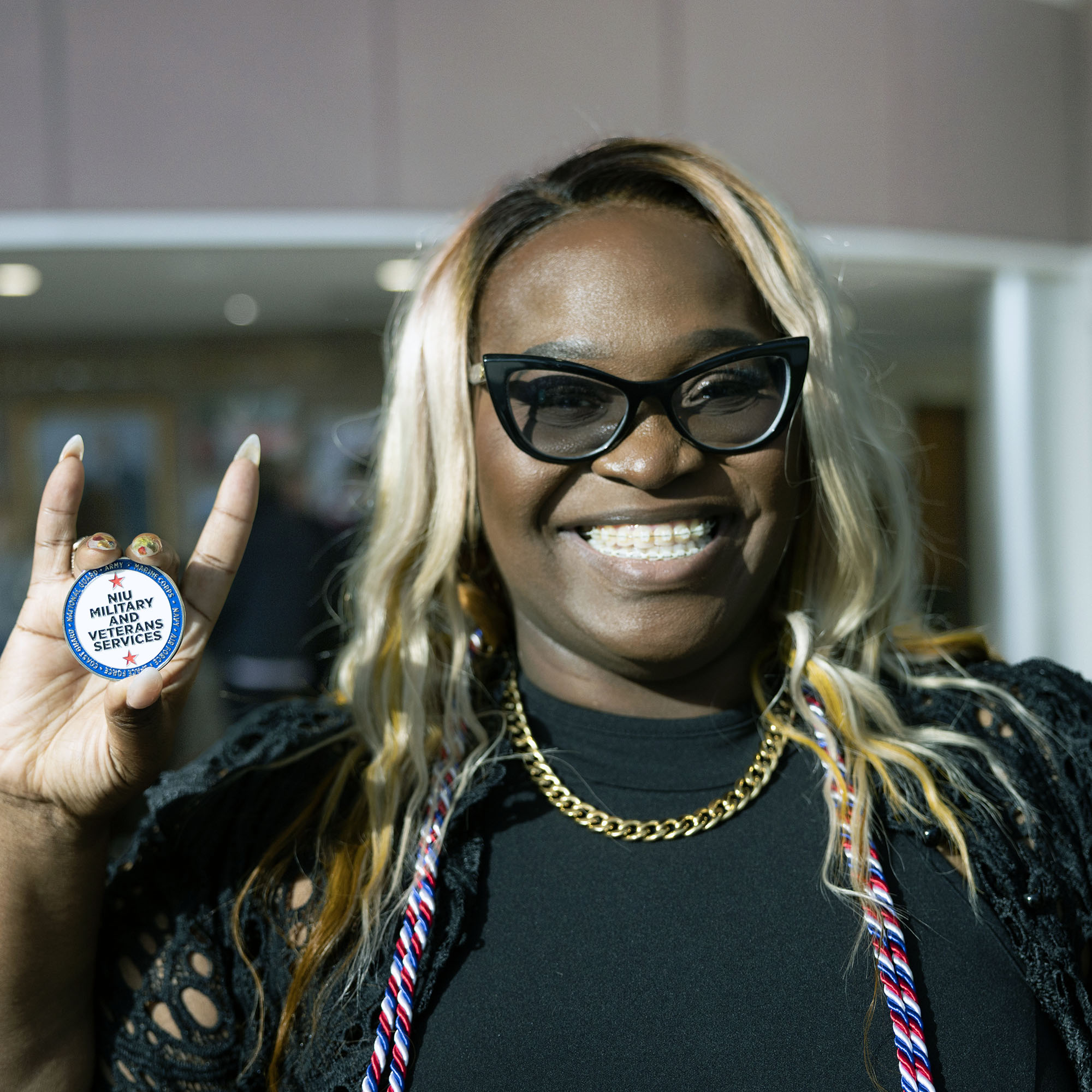 A military-connected graduate holds the NIU Military and Veteran Services coin