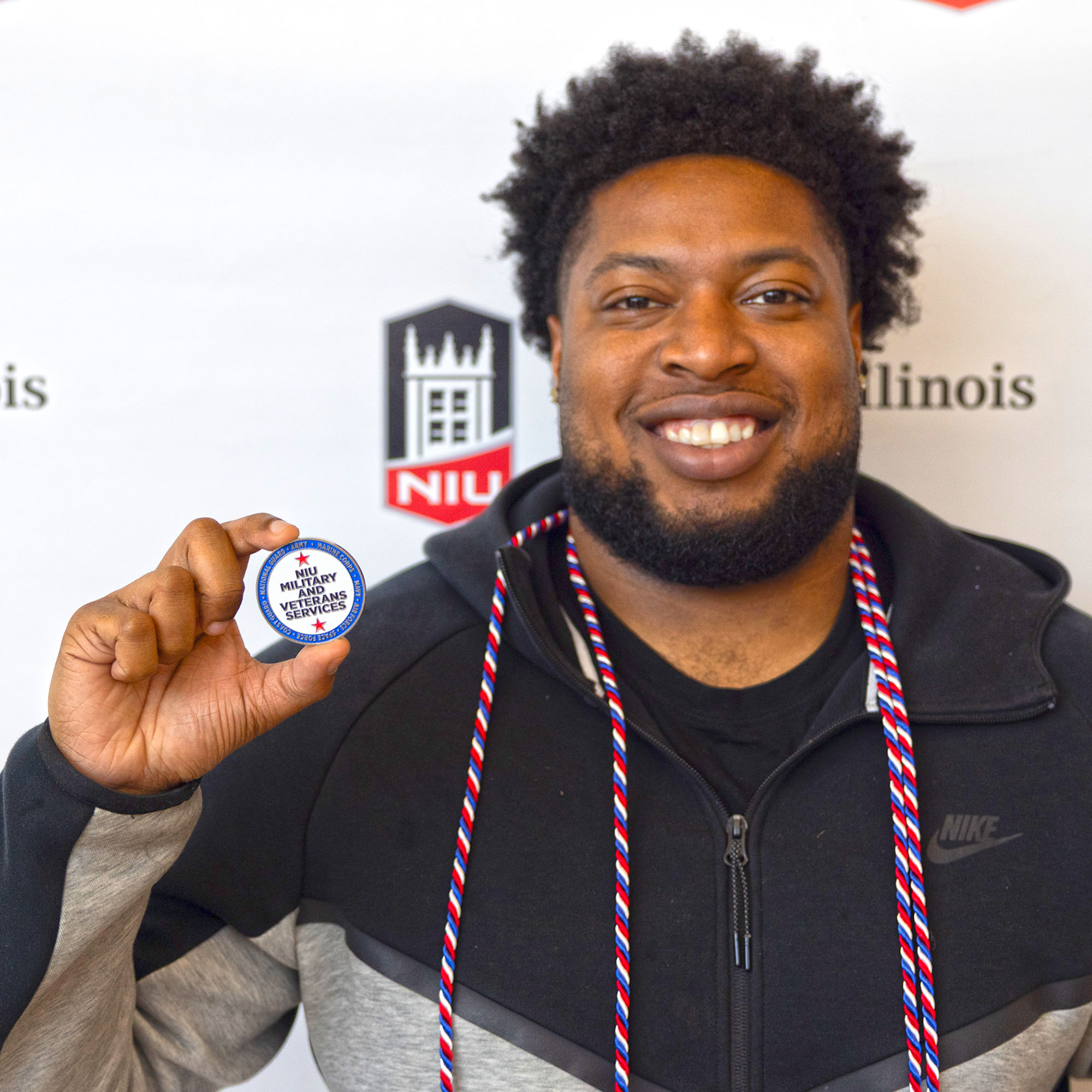 A military-connected graduate holds the NIU Military and Veteran Services coin