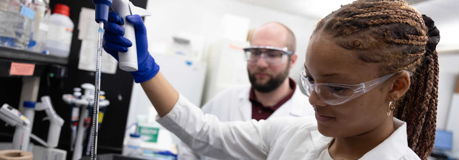 Students with laboratory coats and glasses running tests in a lab