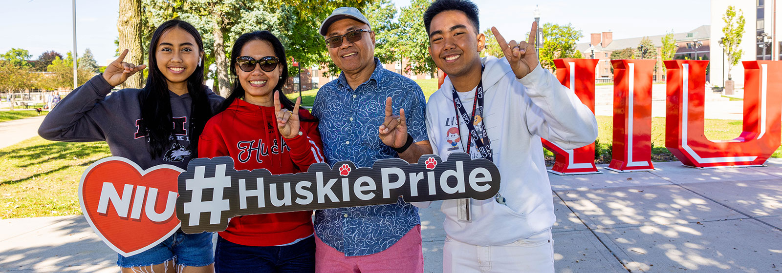 Family of four outside near NU Huskie Pride sculpture